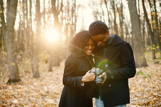 Black couple walking in park and looking in camera in their hands
