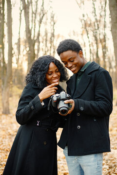 Black couple walking in park and looking in camera in their hands