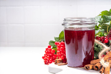 Autumn jam recipe, conservation and harvest season. Homemade red jam from organic viburnum berries, with fresh berries on twigs and cinnamon