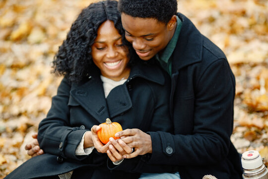 Loving black couple in autumn park looking on little pumpkin