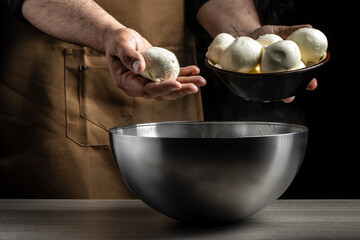 A man working in a small family creamery is processing the final steps of making a cheese. Italian hard cheese silano or caciocavallo, mozzarella