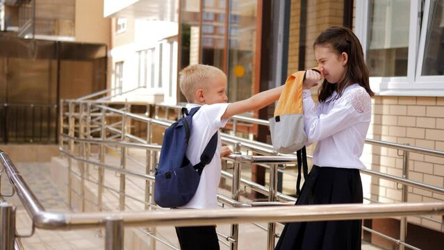 School kids are freaking out on the doorstep of the school. A schoolboy boy accosts a classmate at the entrance to the school.