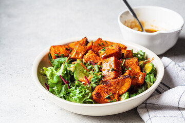 Baked sweet potato salad bowl with mustard dressing. Vegan food concept.