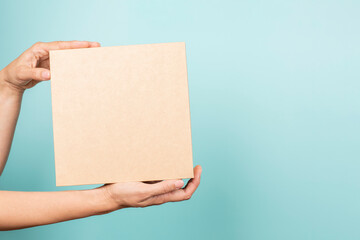 Woman hand show brown rectangular cardboard box on light blue background. Mockup parcel box....