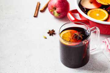 Mulled wine in glass mug, gray background. Autumn or winter cozy drink.