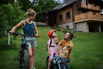 Young family with little children preaparing for bike ride, in front of house.
