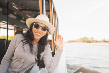 Mujer viajera con sobrero navegando en barco por el rio