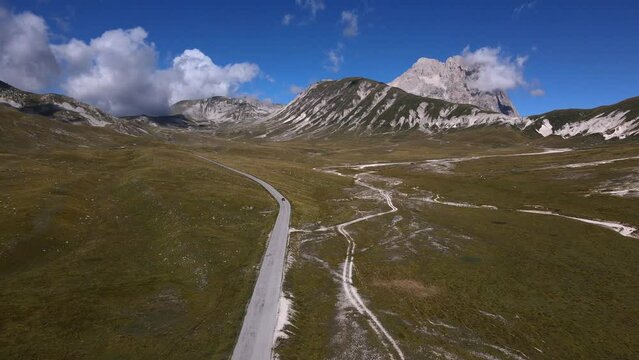 Straight road in the mountains. Gran Sasso mountain, in Abruzzo region, central Italy, summer day in the mountains. Tourist destination in Italy. Drone view