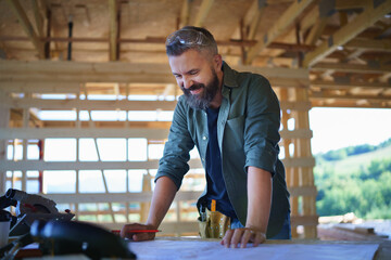 Portrait of construction worker smiling and checking blueprints, diy eco-friendly homes concept.