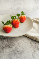strawberries fresh and juicy fruit on white plate and light background minimalist photo