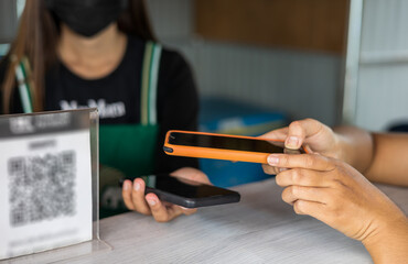 Close up, both hands of a customer holding a mobile phone to scan and transfer payments.