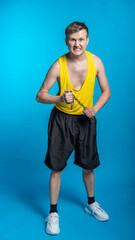 Fototapeta na wymiar a guy in a yellow t-shirt and black shorts holds a short chain. blue background. workout