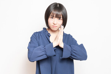 白バックの前で、謝っている若い女性