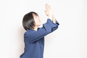 白バックの前で、謝っている若い女性