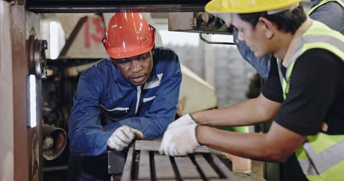 Group of machine technicians are profession inspect the electrical equipment in factory. Industrial plant engineers plan machine maintenance. African American workers work with Asian team Blue collar