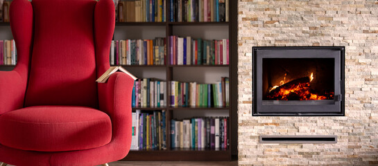Red, comfortable armchair  background of the library books. Fireplace with fire. Autumn relaxation,...