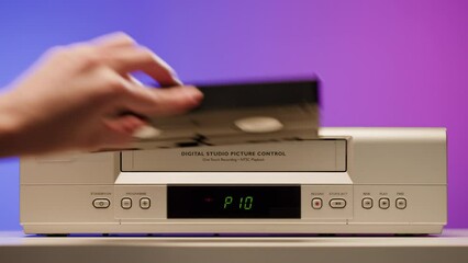 Old video recorder close-up, VHS. Retro player, vintage video cassette broadcasting on purple background, audio tape. 