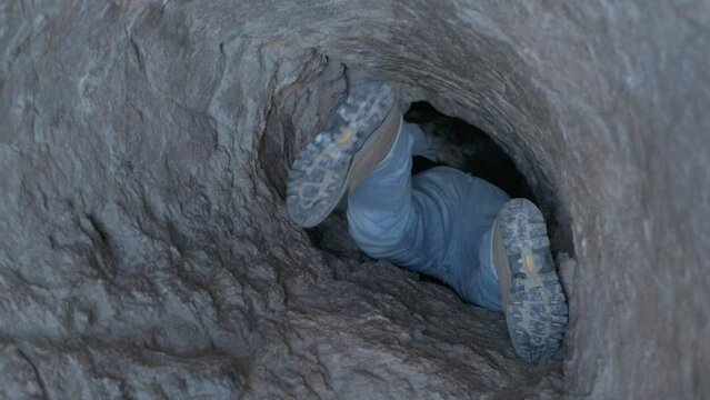 une personne rampe dans un tunnel pour une exploration de cave