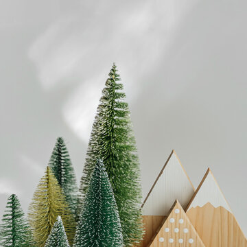 Miniature fir trees and mountains on white background. Winter cute landscape. Cozy small world. Christmas decorations, holiday concept.