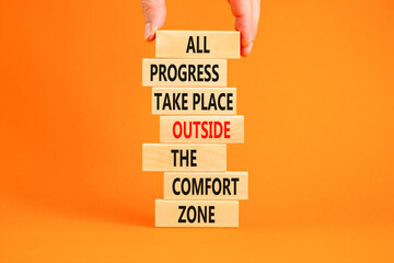 Progress symbol. Concept words All progress take place outside the comfort zone on wooden blocks on a beautiful orange background. Businessman hand. Business motivational and progress concept.