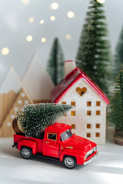 Miniature houses and fir trees with red car with Christmas Tree on white background. Winter cute landscape. Cozy small world. Christmas decorations, holiday concept.