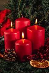 Three burning Red advent candles in advent wreath decoration on wooden dark background. tradition in time before Christmas. xmas lights with christmas fir deco background concept. Festive still life.