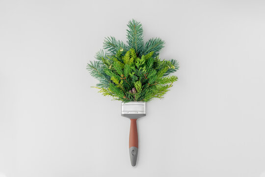 Creative Christmas concept on white background with copy space. Paintbrush with spruce branches.