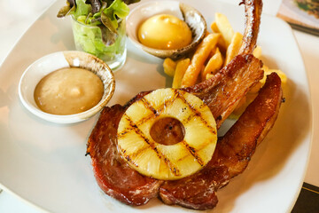 Grilled pork chop steak with pineapple, French fried and salad on white dish