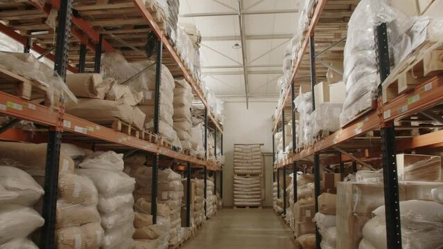 Slow tracking shot inside big warehouse with bags of spices on rack shelves ready for shipment