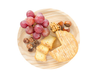 Soft washed-rind cheese, hazelnuts, walnut and red grape on the textured wooden board top view...