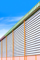 Perspective side view of aluminum louver with gutter drainage system of warehouse building against blue sky in vertical frame