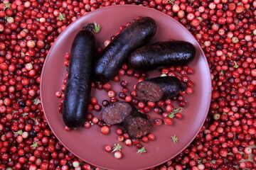 Baked blood sausage on a red plate decorated with red cranberries, Traditional Latvian blood...