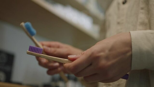Shopper woman in the store chooses eco-friendly wooden toothbrushes close-up