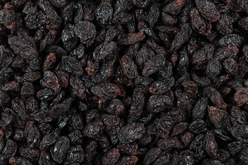 .Dried black raisins in a copper bowl, scatchered raisins around a copper bowl of raisins.