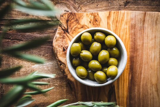 vista superior de un bol de aceitunas, sobre una tabla de cortar de madera de olivo