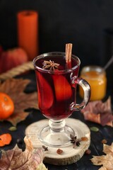 Non-alcoholic mulled wine with orange, cinnamon and honey on a wooden stand. Autumn mood.