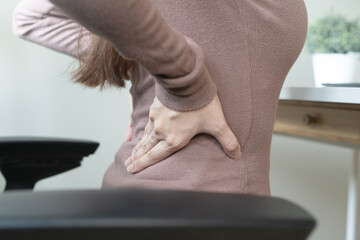 office syndrome, woman with back pain symptoms during work in the office.