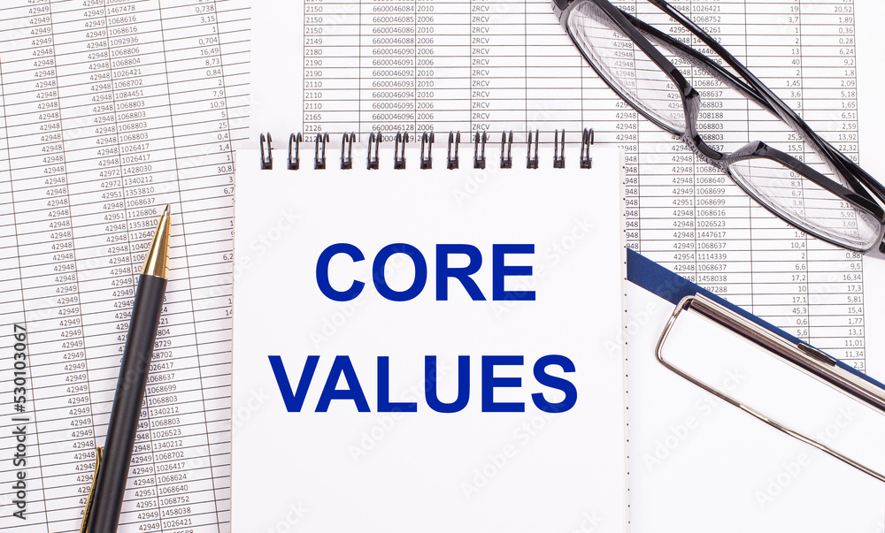 Aufkleber a white notepad with the text core values, a pen, reports and glasses lie on a white office table. v