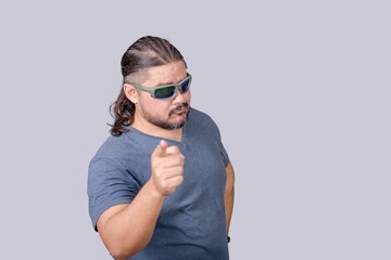 A man wearing shades acting tough while making a stern warning with his finger. Isolated on a gray...