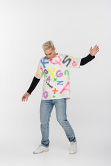 full length of gay man in alphabet print t-shirt posing on grey background.