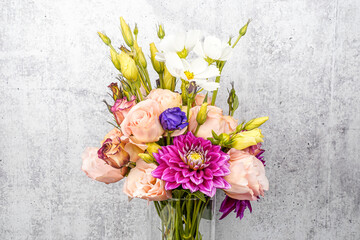 Bouquet of garden picked flowers in a glass vase. Gray background. Graphic resource. Dahlias and lisianthus flowers. Space for text.