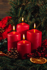 four burning Red advent candles in advent wreath decoration on wooden dark background. tradition in...