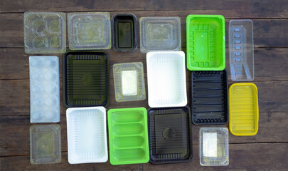 Multi-colored disposable plastic food containers are laid out on a wooden floor. plastic pollution