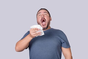 A man in his 30s is about to sneeze into a tissue paper. Triggered by an allergy or a cold.