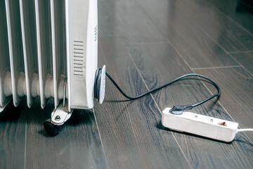 oil electric heater on a wooden floor is plugged into a socket. Building space heating