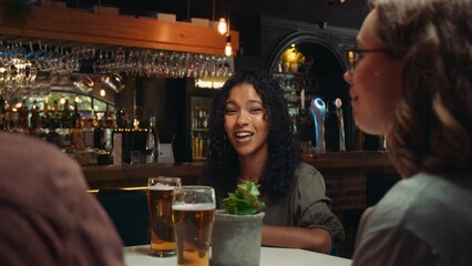 Diverse group of friends out for dinner chatting around table