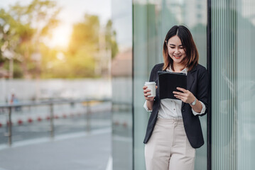 Fototapeta premium Young Asian businesswoman talking on phone and sitting in airport before business trip. Beautiful woman passenger has mobile call and discusses something with smile, holds coffee in hand
