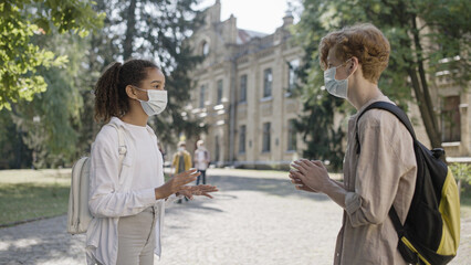 Multiethnic school children in face masks talking, schooling during pandemic