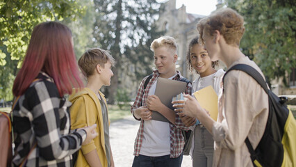 Happy school friends hanging out together outdoor, multiracial friendship