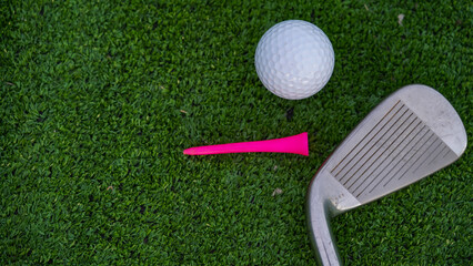 Golf clubs and golf balls on a green lawn in a beautiful golf course.